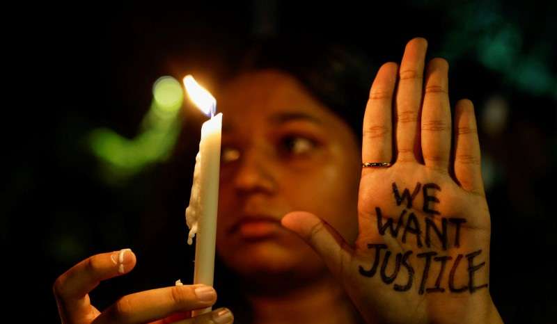 A woman holds a candle during a vigil condemning the rape and murder of a trainee medic at a government-run hospital in Kolkata, on a street in Mumbai
