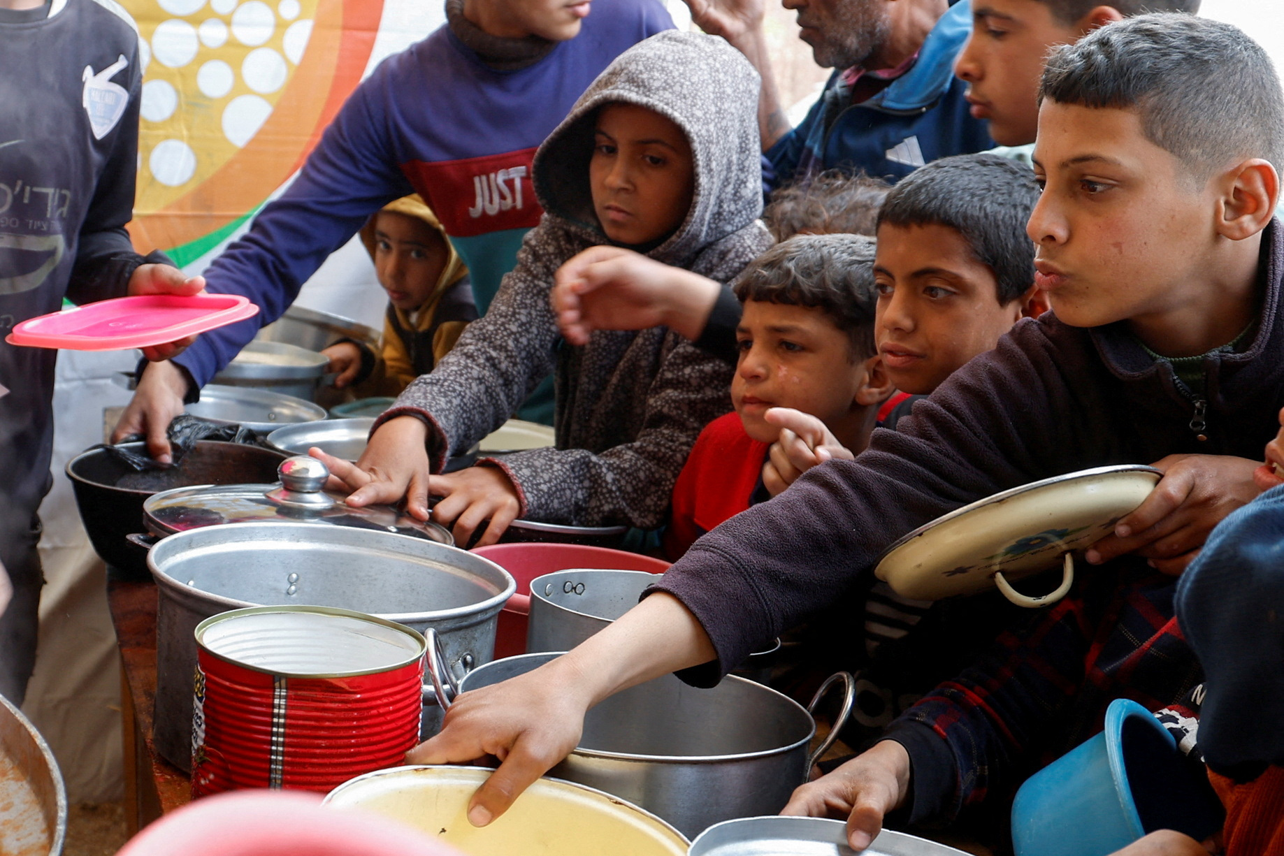 FILE PHOTO: Palestinians gather to receive food cooked by a charity kitchen, in Khan Younis