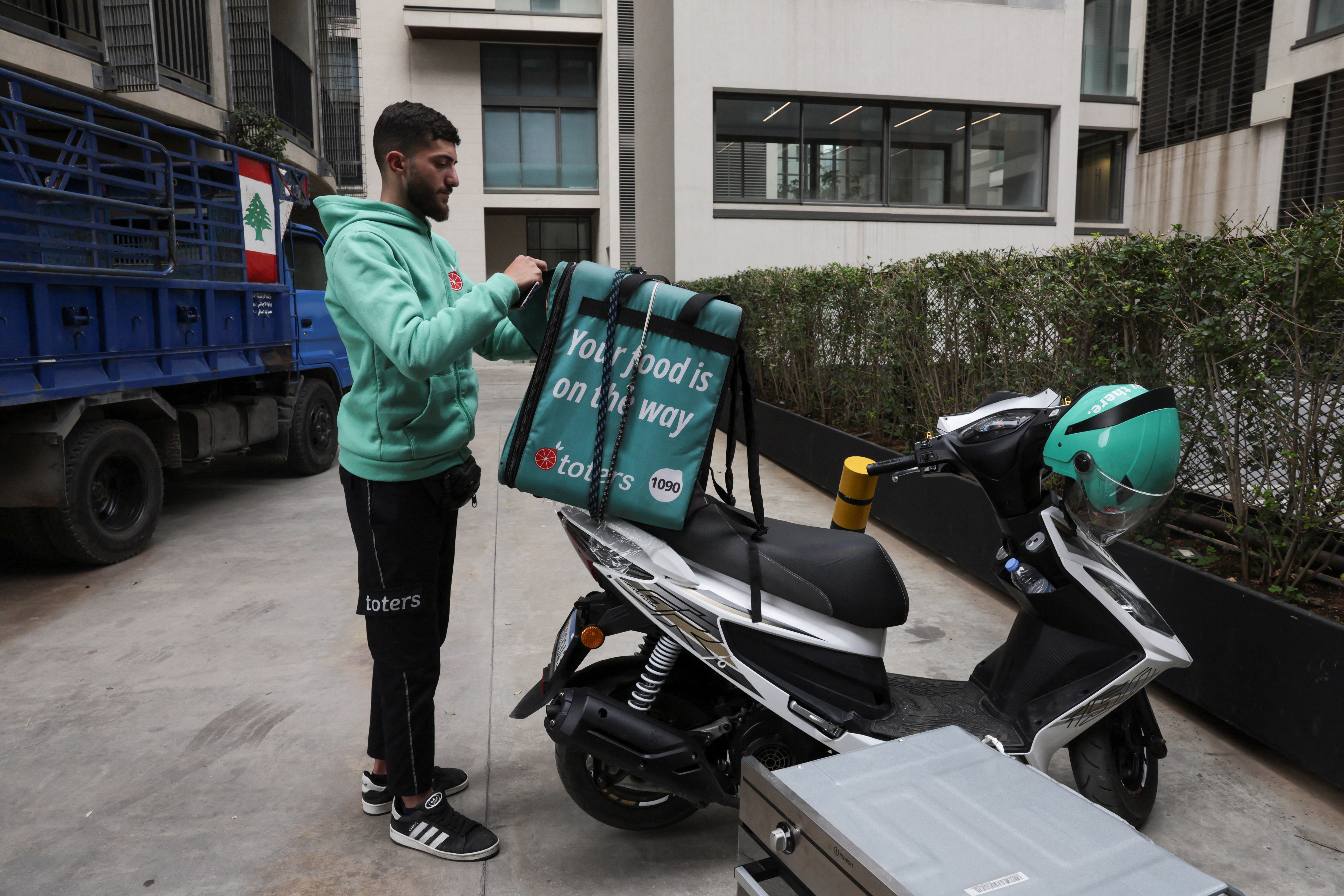 Hamza Hareb, who works as a delivery driver for the Toters delivery app opens his courier's backpack to drop a delivery in Beirut