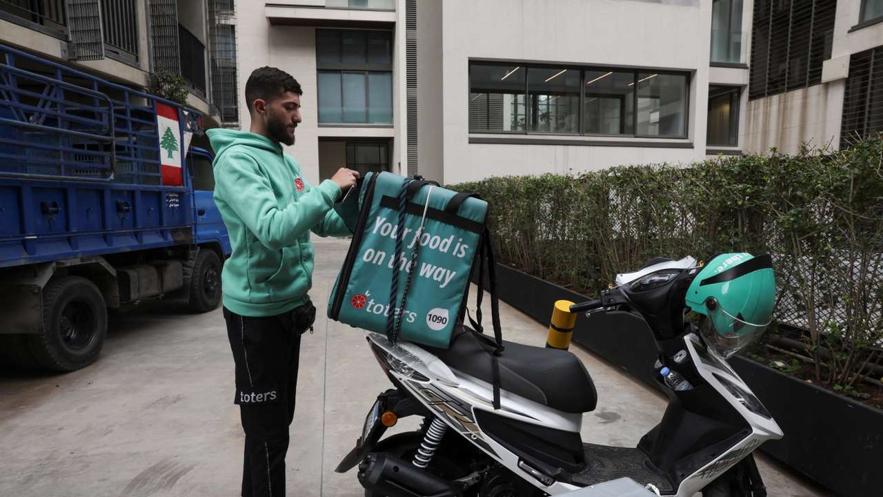 Hamza Hareb, who works as a delivery driver for the Toters delivery app opens his courier's backpack to drop a delivery in Beirut