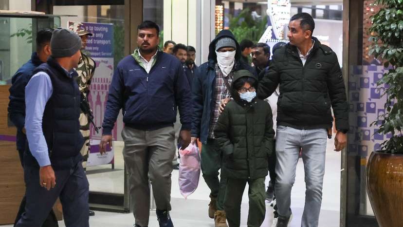 Security personnel escort Indian immigrants deported from the U.S., as they leave the airport in Ahmedabad