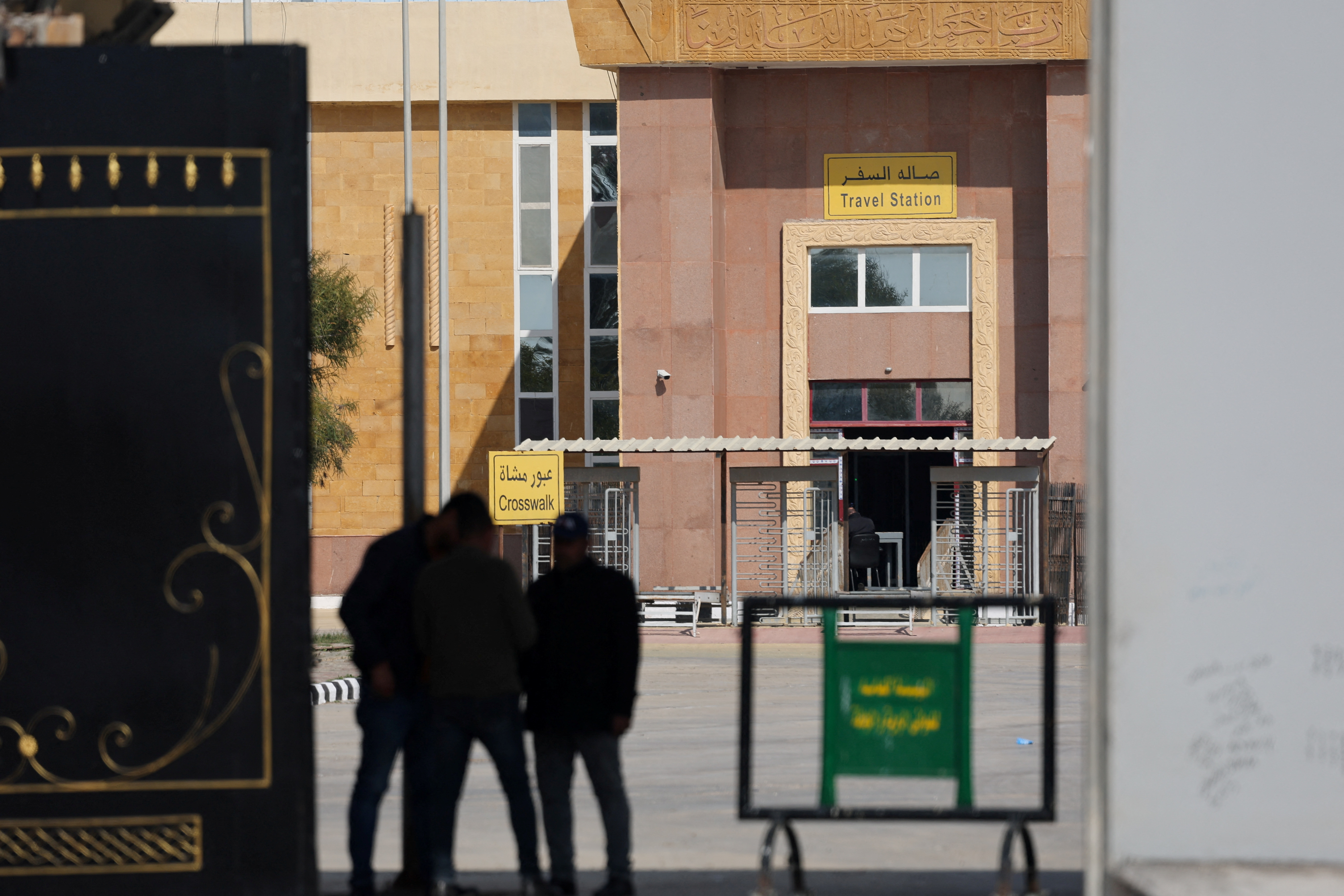 People stand at the gate of the border crossing between Egypt and the Gaza Strip