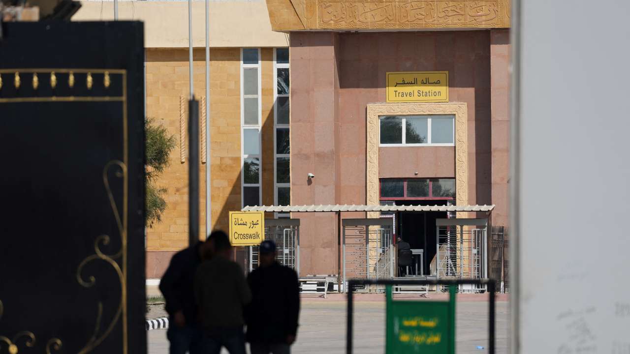 People stand at the gate of the border crossing between Egypt and the Gaza Strip