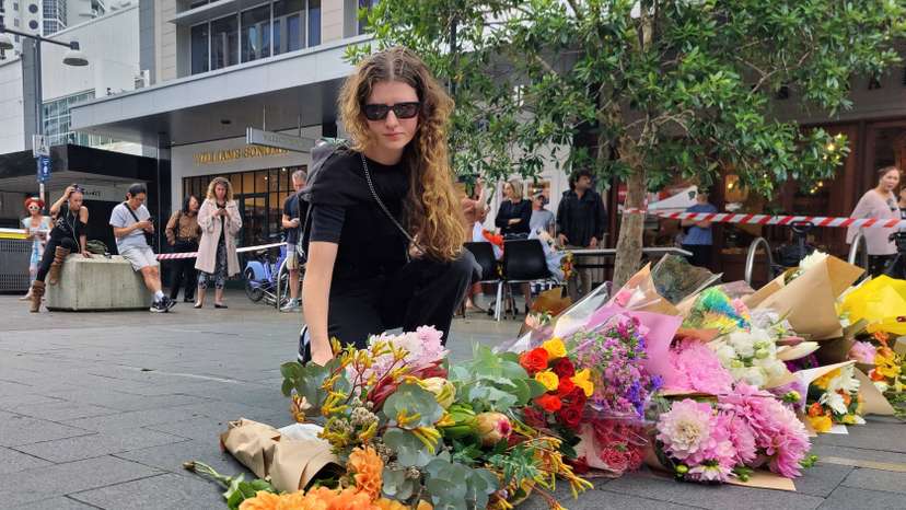 People offer flowers for the victims of Saturday's stabbings at Bondi Junction in Sydney