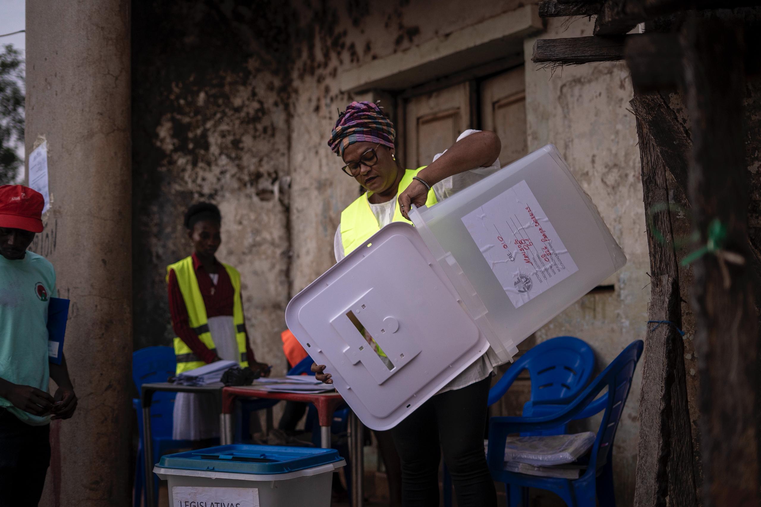 A polling agent displays an empty ballot box to citizens for transparency. Photo Credit: Samba M. Balde