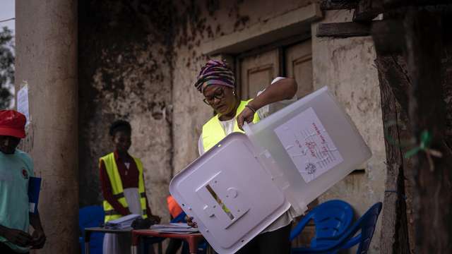A polling agent displays an empty ballot box to citizens for transparency. Photo Credit: Samba M. Balde