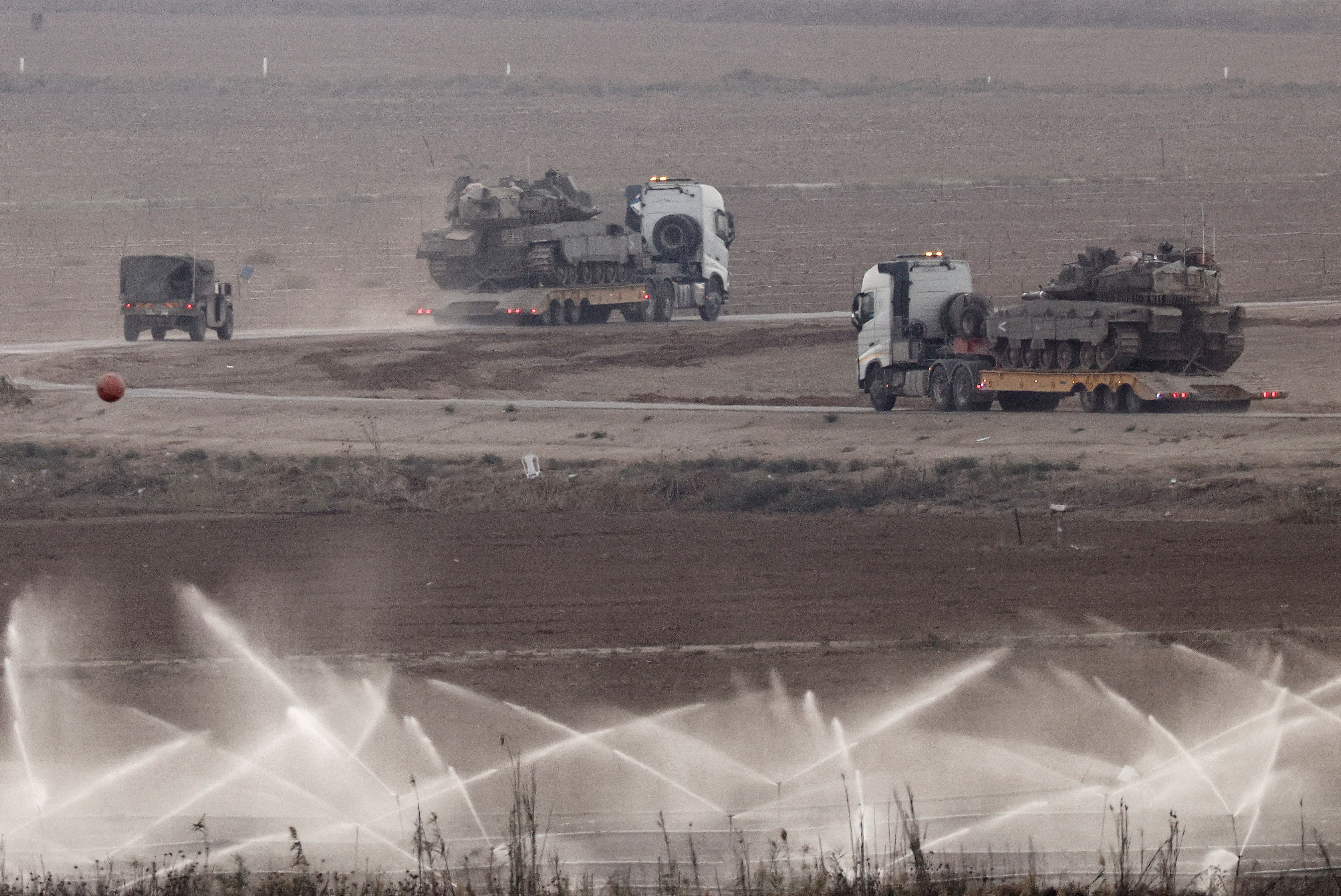 Trucks transport tanks on the Israeli side of the border with Gaza