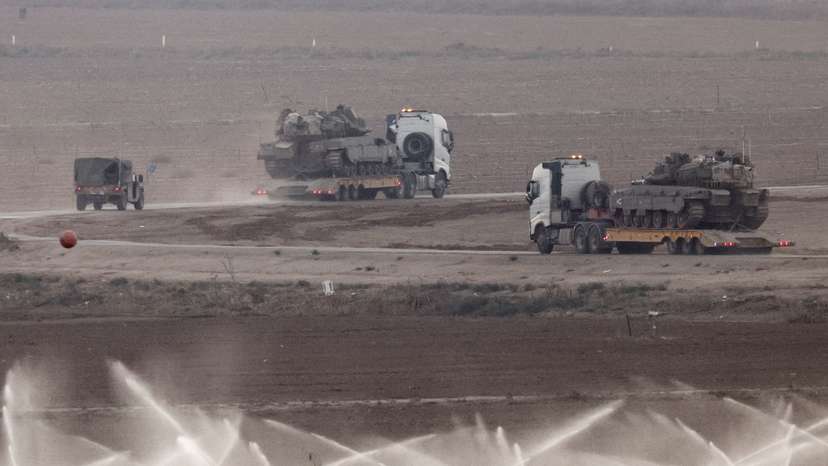 Trucks transport tanks on the Israeli side of the border with Gaza