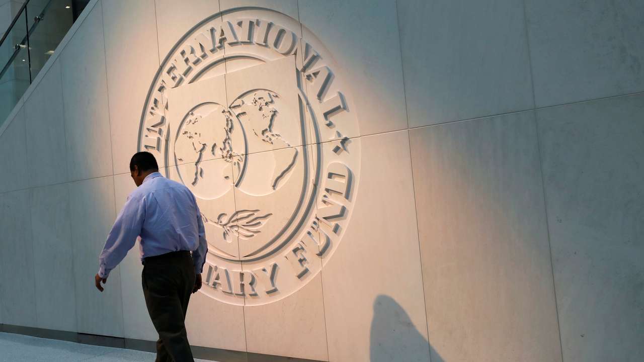 Man walks past the IMF logo at HQ in Washington