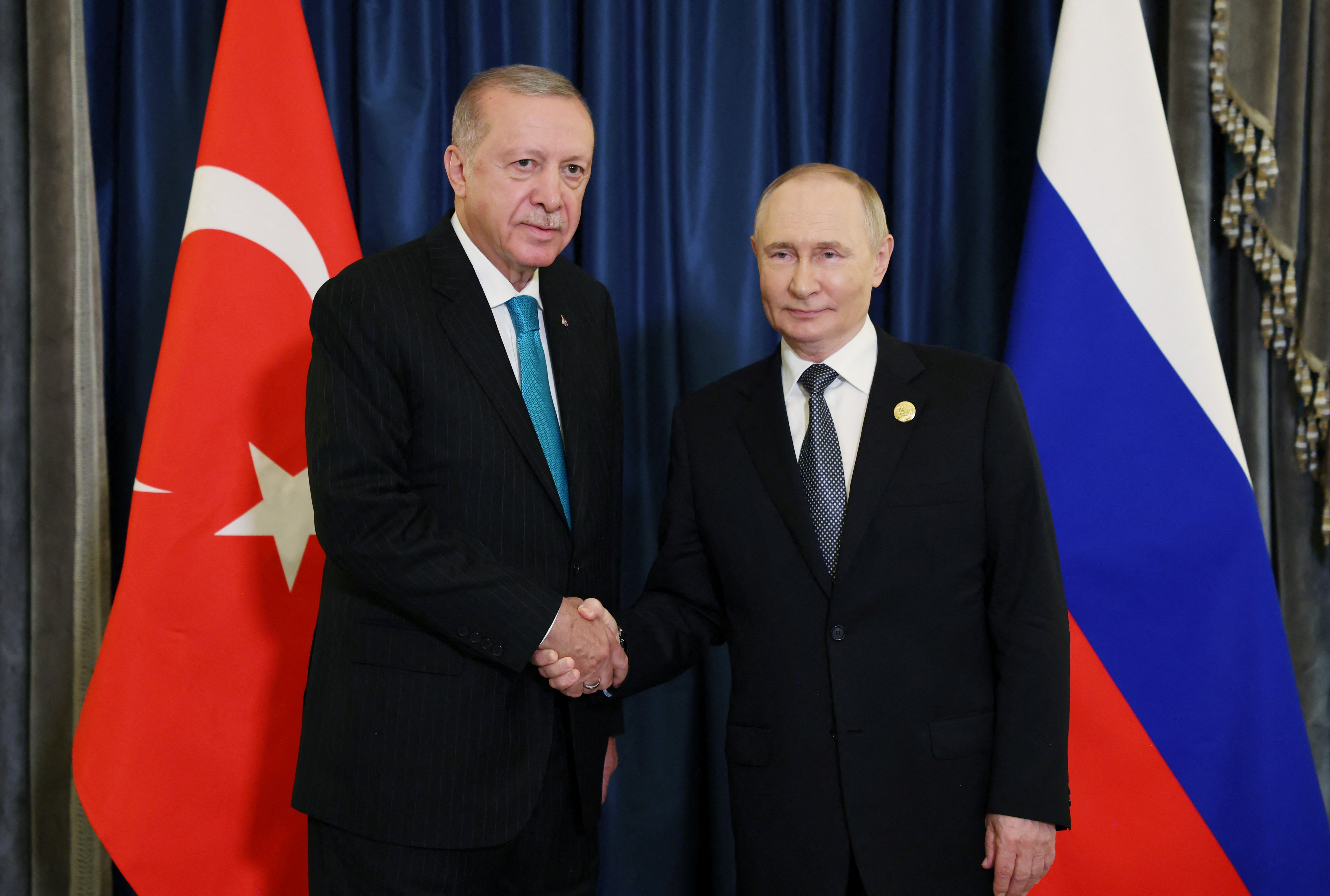 Turkish President Erdogan shakes hands with Russia's President Putin during a meeting in Tianjin