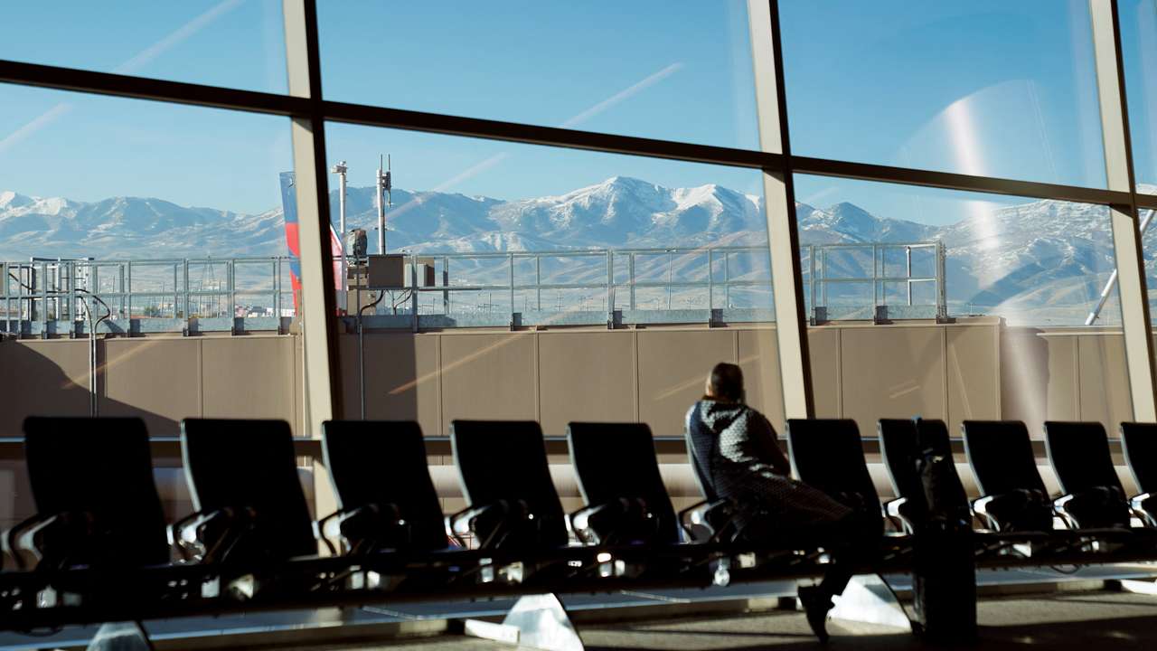 With the Wasatch Mountains in the background, a passenger waits at Salt Lake City International Airport in Utah
