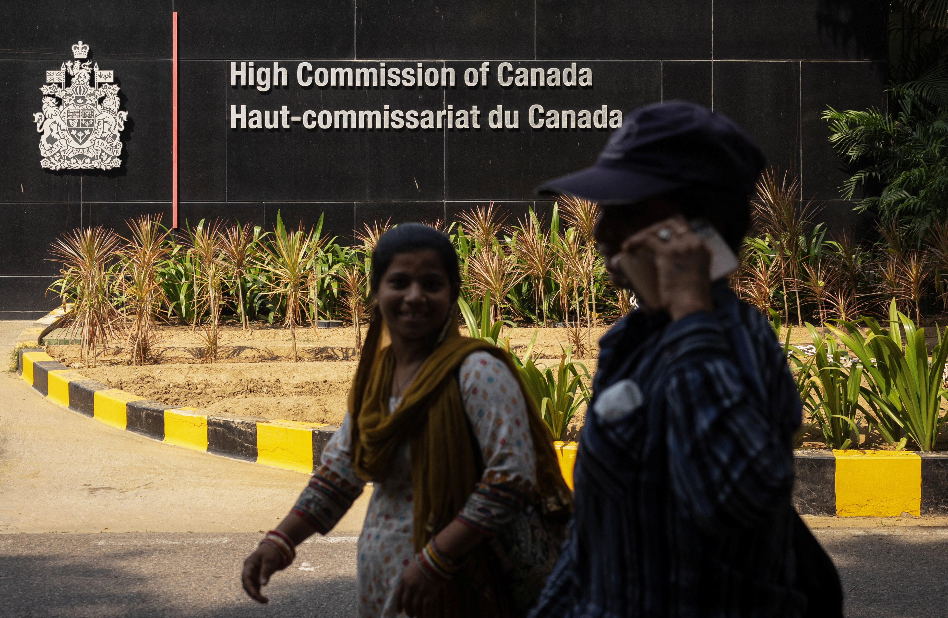 Women walk past the main gate of the Canadian High Commission in New Delhi