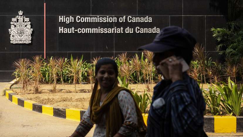 Women walk past the main gate of the Canadian High Commission in New Delhi