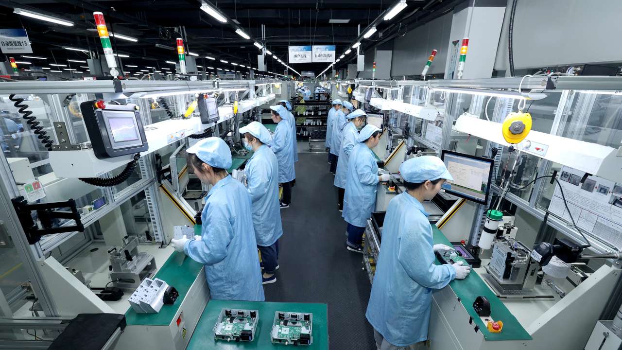 Workers work on a production line manufacturing smart automotive central control navigation products at a factory in Suqian