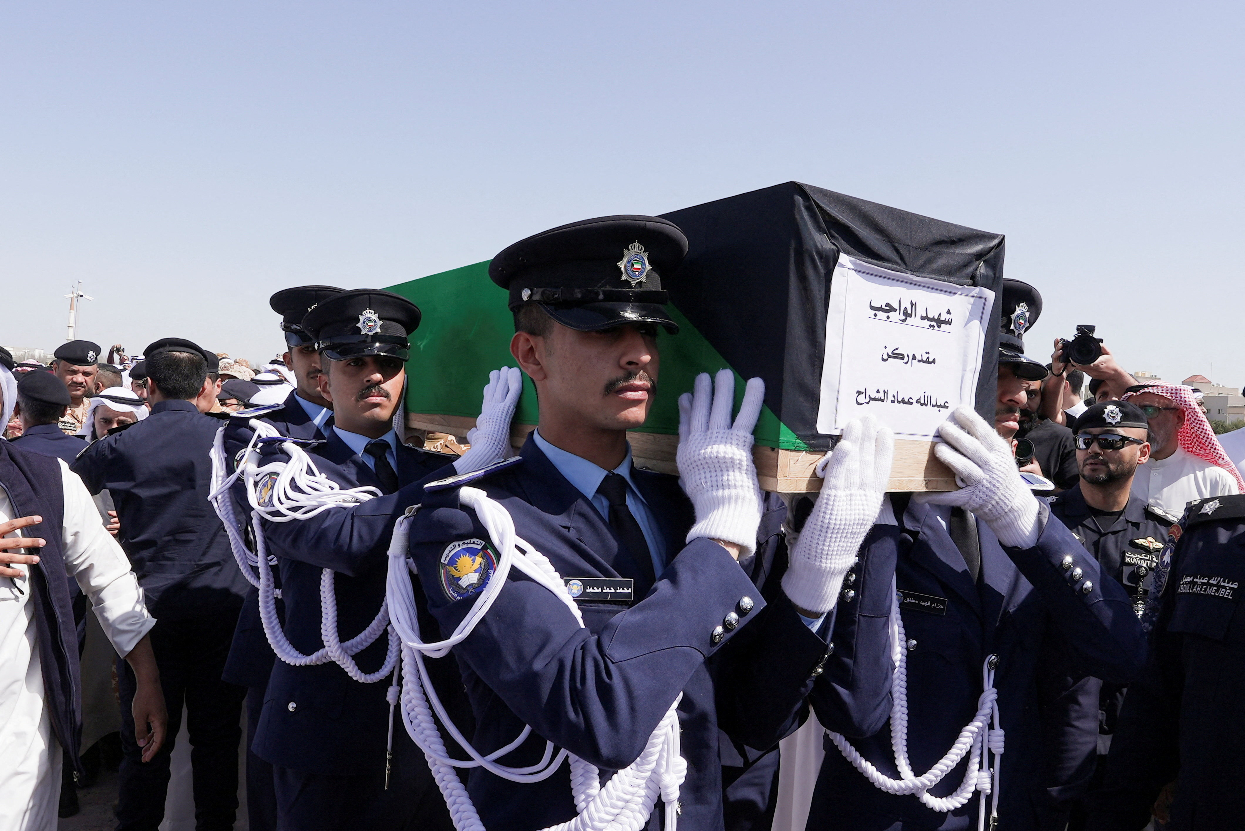 Guards of Honour carry the coffin of one of two police officers, who were killed while performing their duties, during their funeral procession at a graveyard in Kuwait City