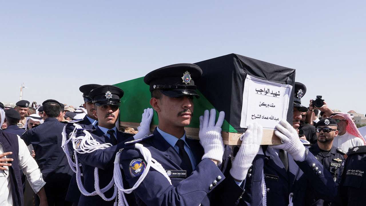 Guards of Honour carry the coffin of one of two police officers, who were killed while performing their duties, during their funeral procession at a graveyard in Kuwait City