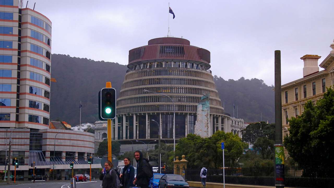 FILE PHOTO: Pedestrians walk across a road in front of the New Zealand parliament building