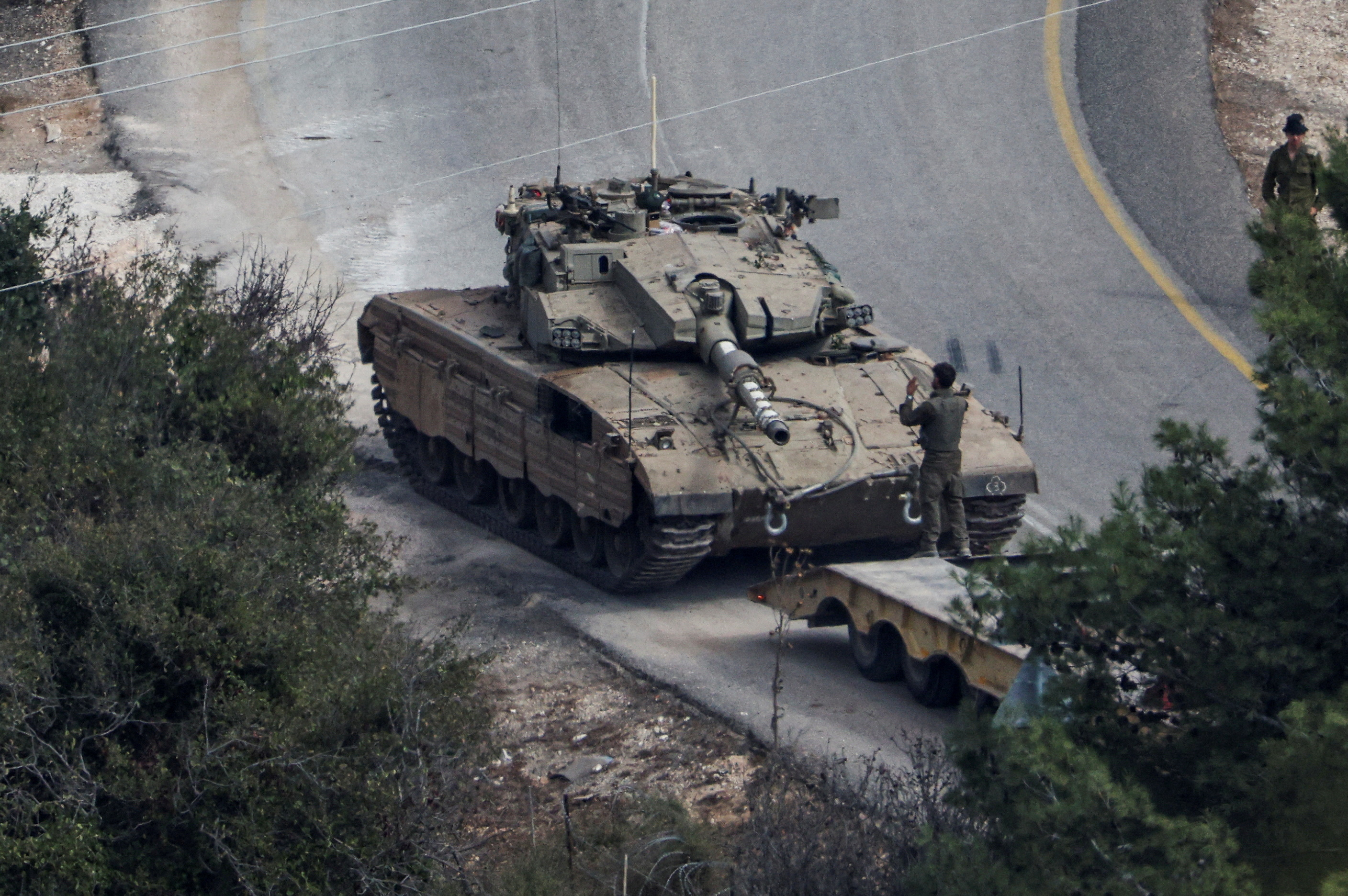 An Israeli tank is loaded on a truck, amid ongoing hostilities between Hezbollah and Israeli forces