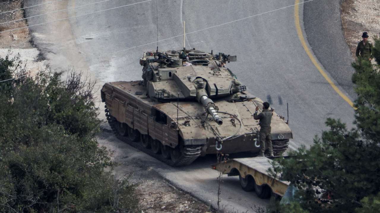 An Israeli tank is loaded on a truck, amid ongoing hostilities between Hezbollah and Israeli forces