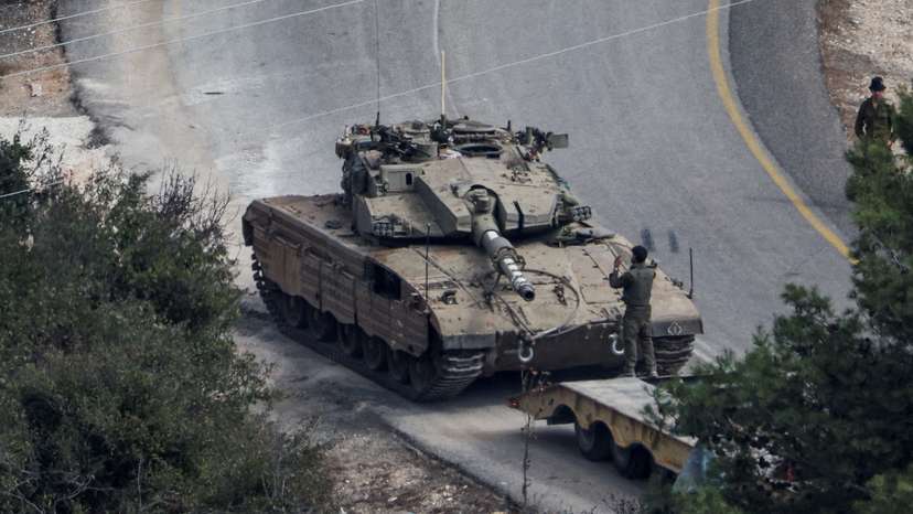 An Israeli tank is loaded on a truck, amid ongoing hostilities between Hezbollah and Israeli forces