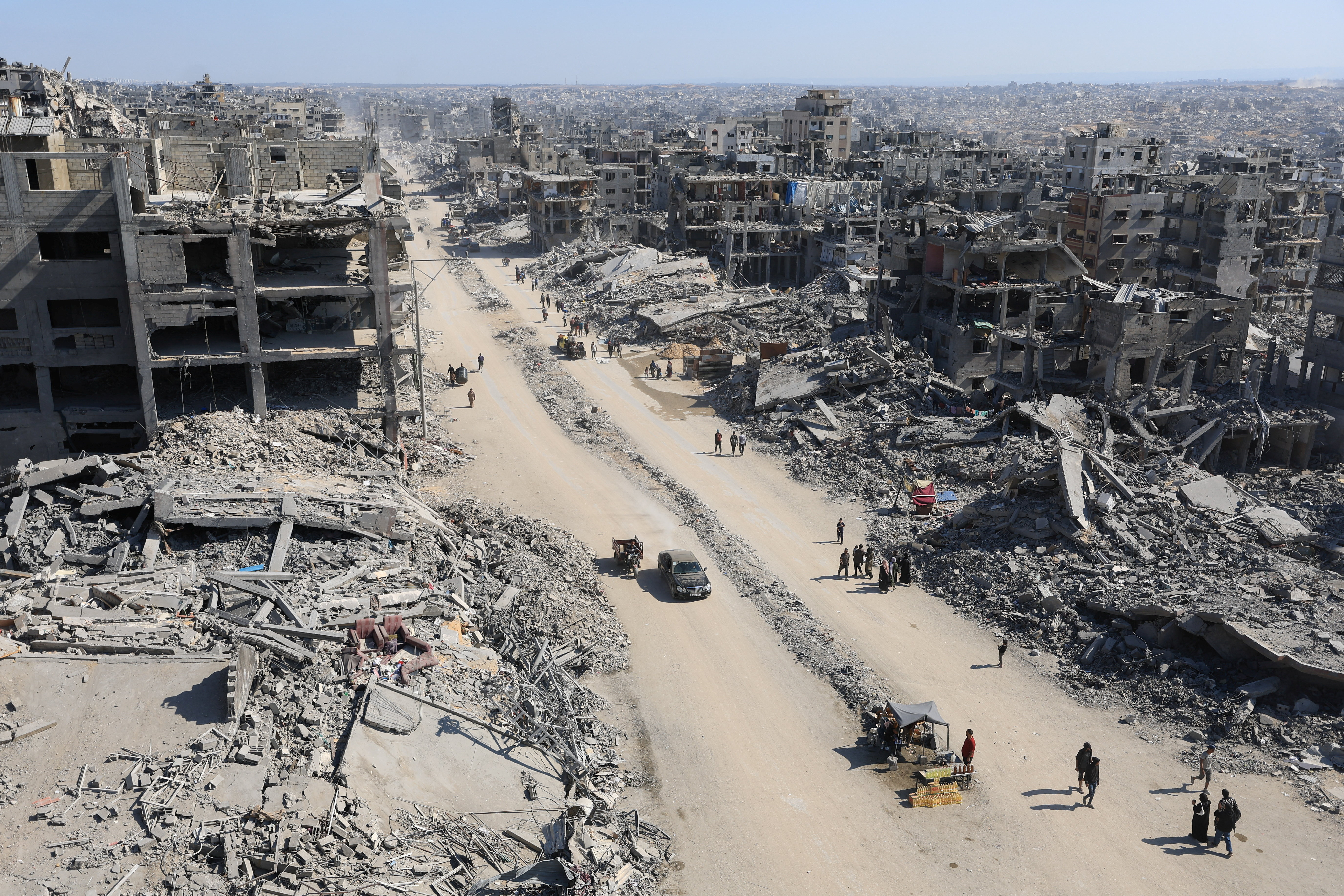 Palestinians walk past the rubble of destroyed buildings, in Gaza City