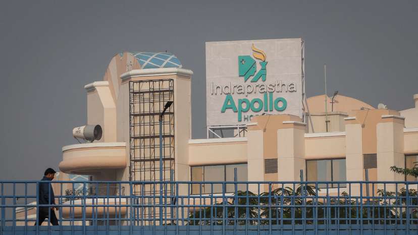 A man walks on a pedestrian bridge in front of an Apollo hospital building in New Delhi