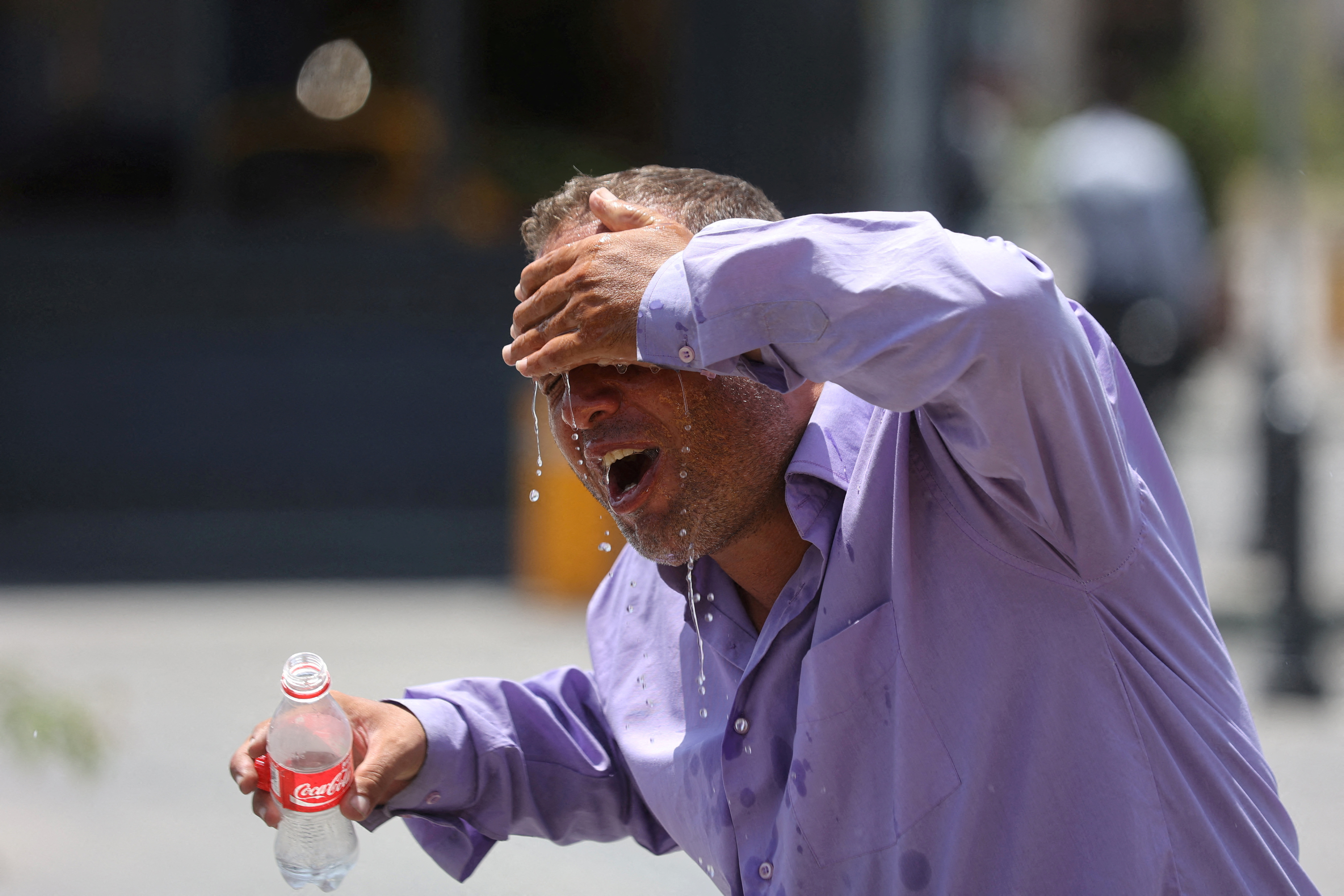 An Iranian taxi driver splashes water on himself to cool down during the heat surge in Tehran.