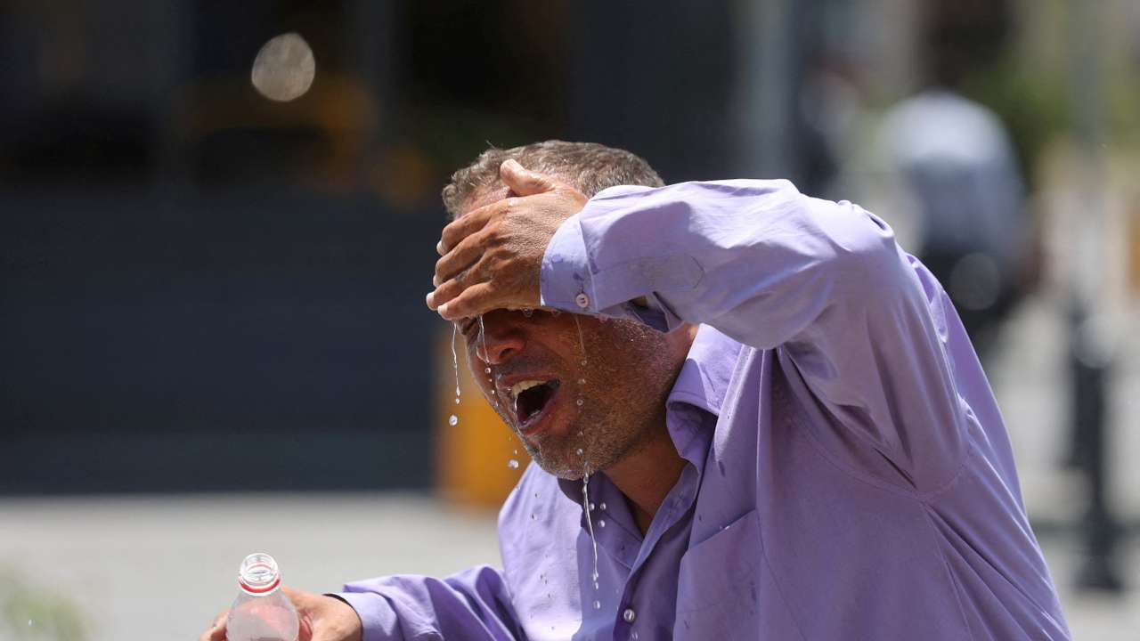 An Iranian taxi driver splashes water on himself to cool down during the heat surge in Tehran.