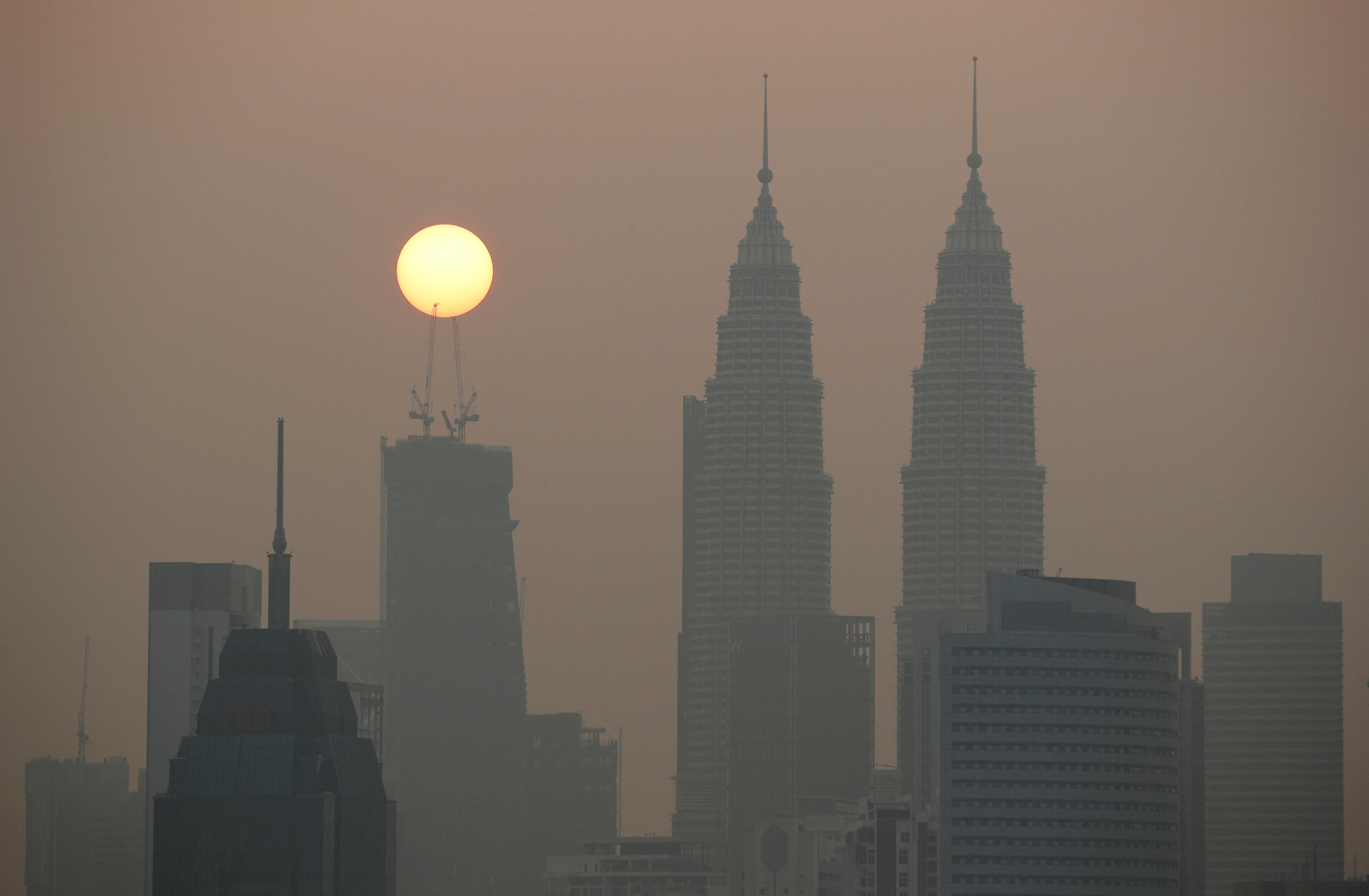 FILE PHOTO: Sun rises above Kuala Lumpur's skyline on a hazy day in Kuala Lumpur