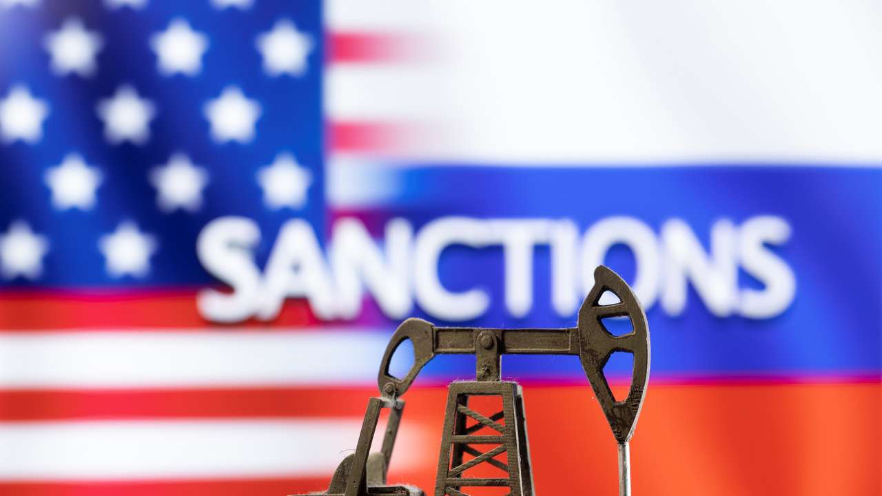Illustration shows pump jack in the front word "Sanctions", U.S. and Russia flag colours