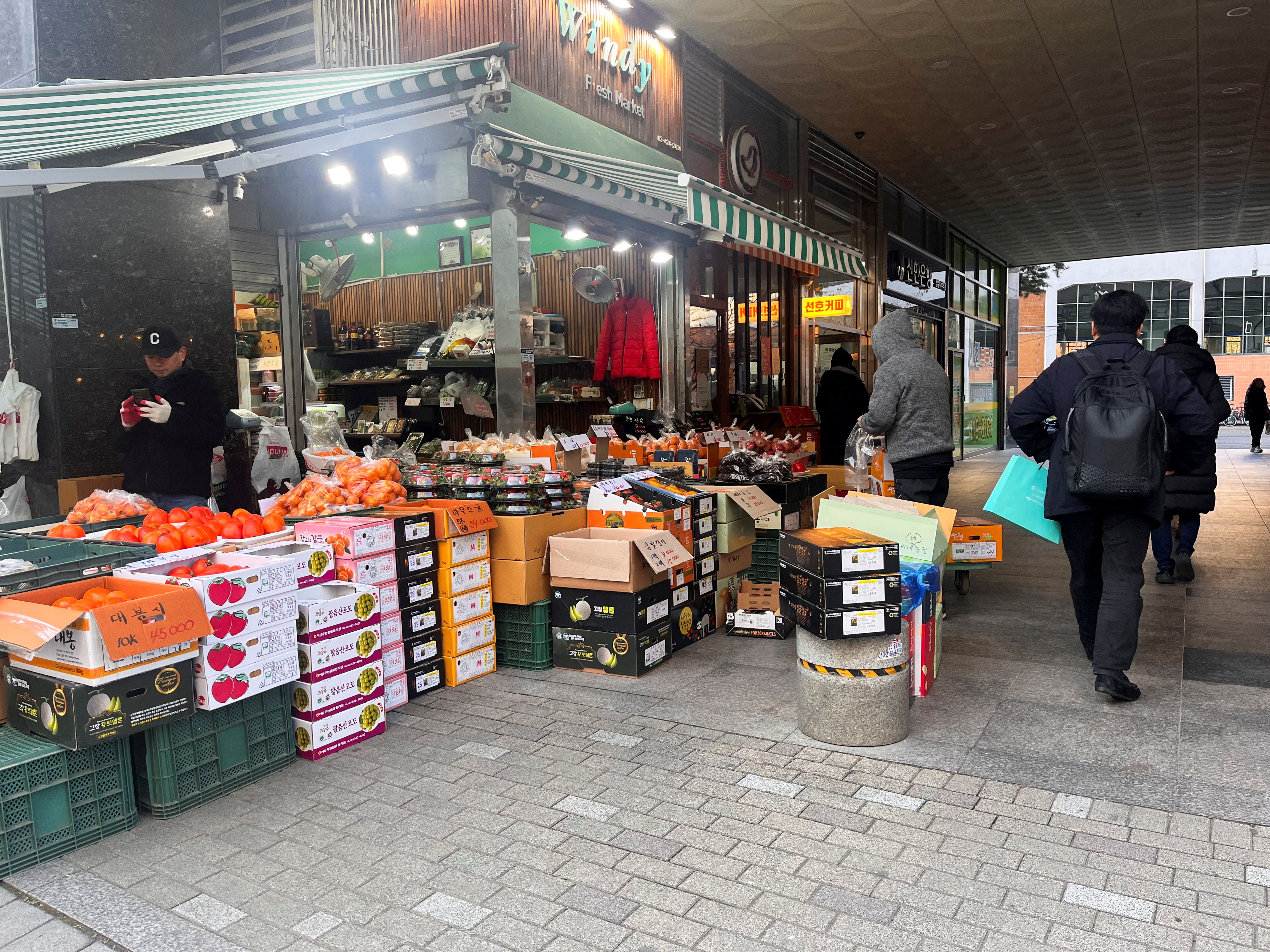 People walk next to a fresh produce stall, in Seoul