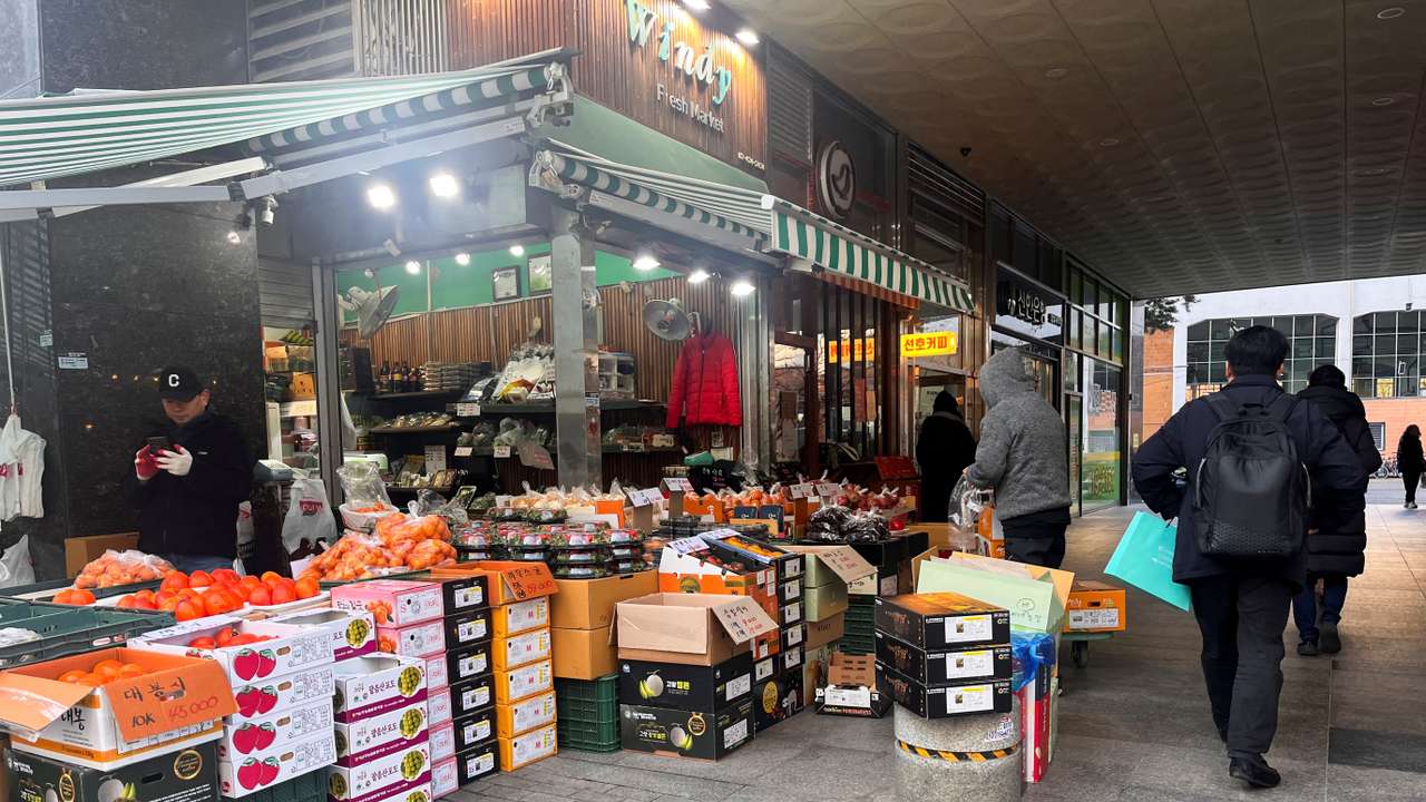 People walk next to a fresh produce stall, in Seoul