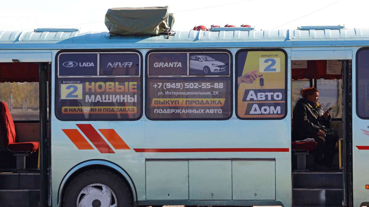 A woman sits inside a bus with a drone jamming device installed on the roof in Horlivka