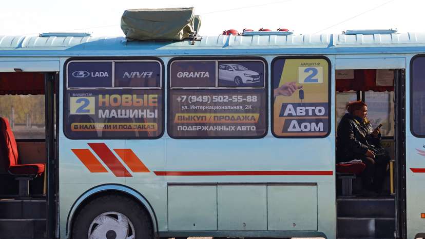 A woman sits inside a bus with a drone jamming device installed on the roof in Horlivka
