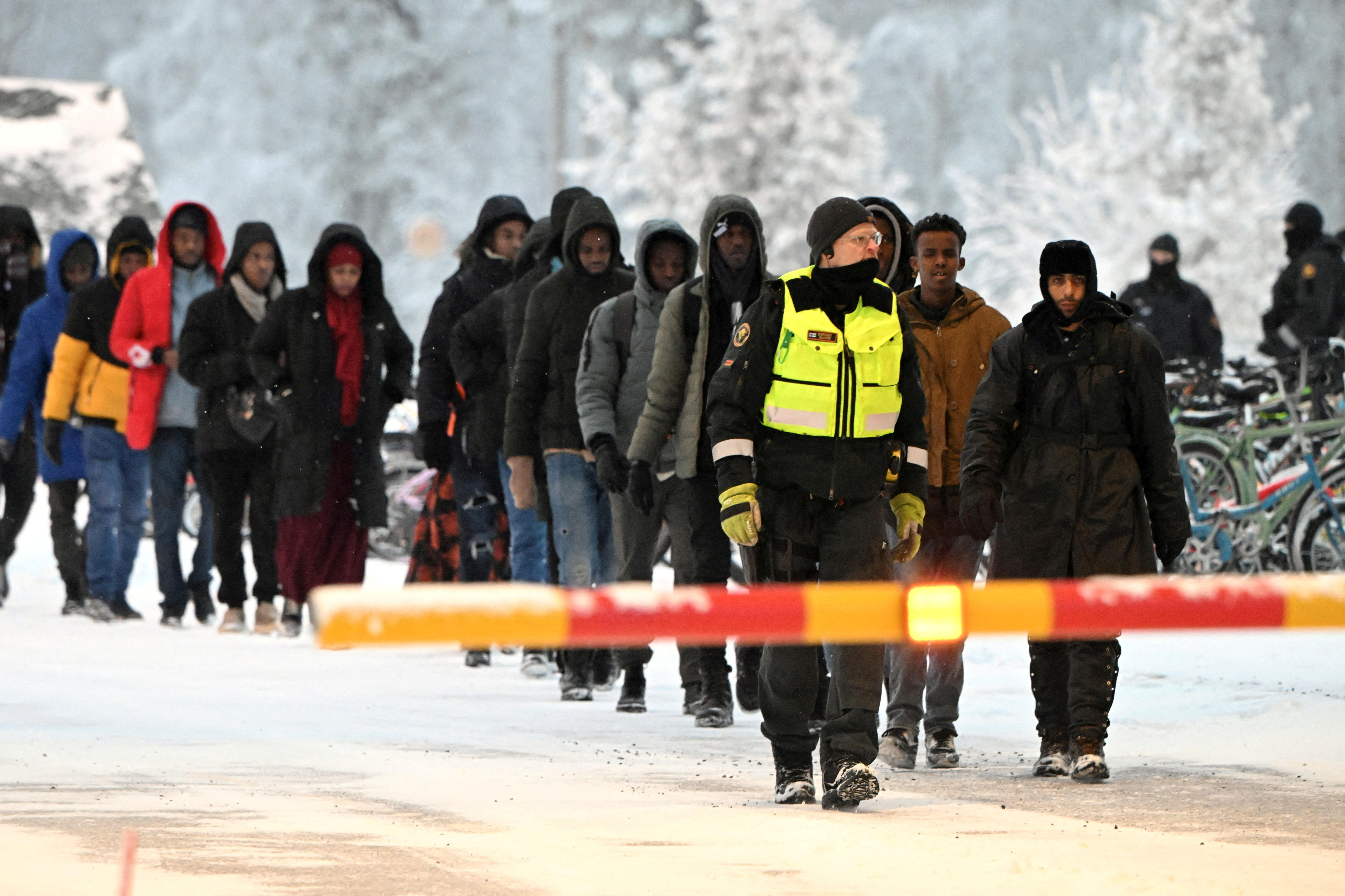 FILE PHOTO: Finnish Border Guards escort the migrants at the international border crossing at Salla