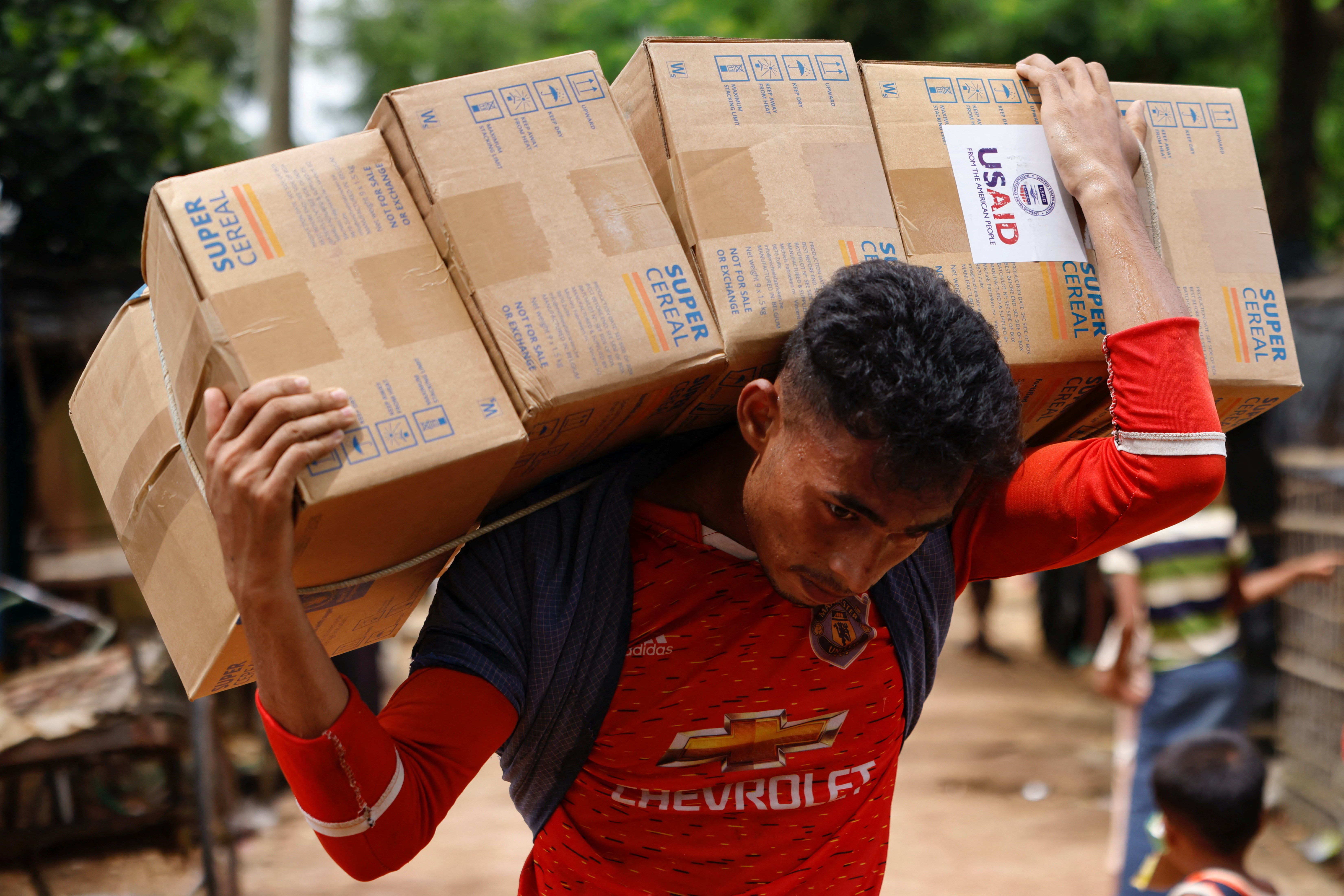 A Rohingya man carries USAID packages as he transports them to warehouse at a refugee camp in Cox's Bazar
