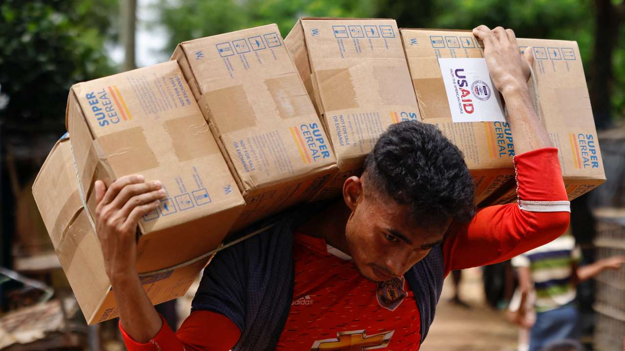 A Rohingya man carries USAID packages as he transports them to warehouse at a refugee camp in Cox's Bazar