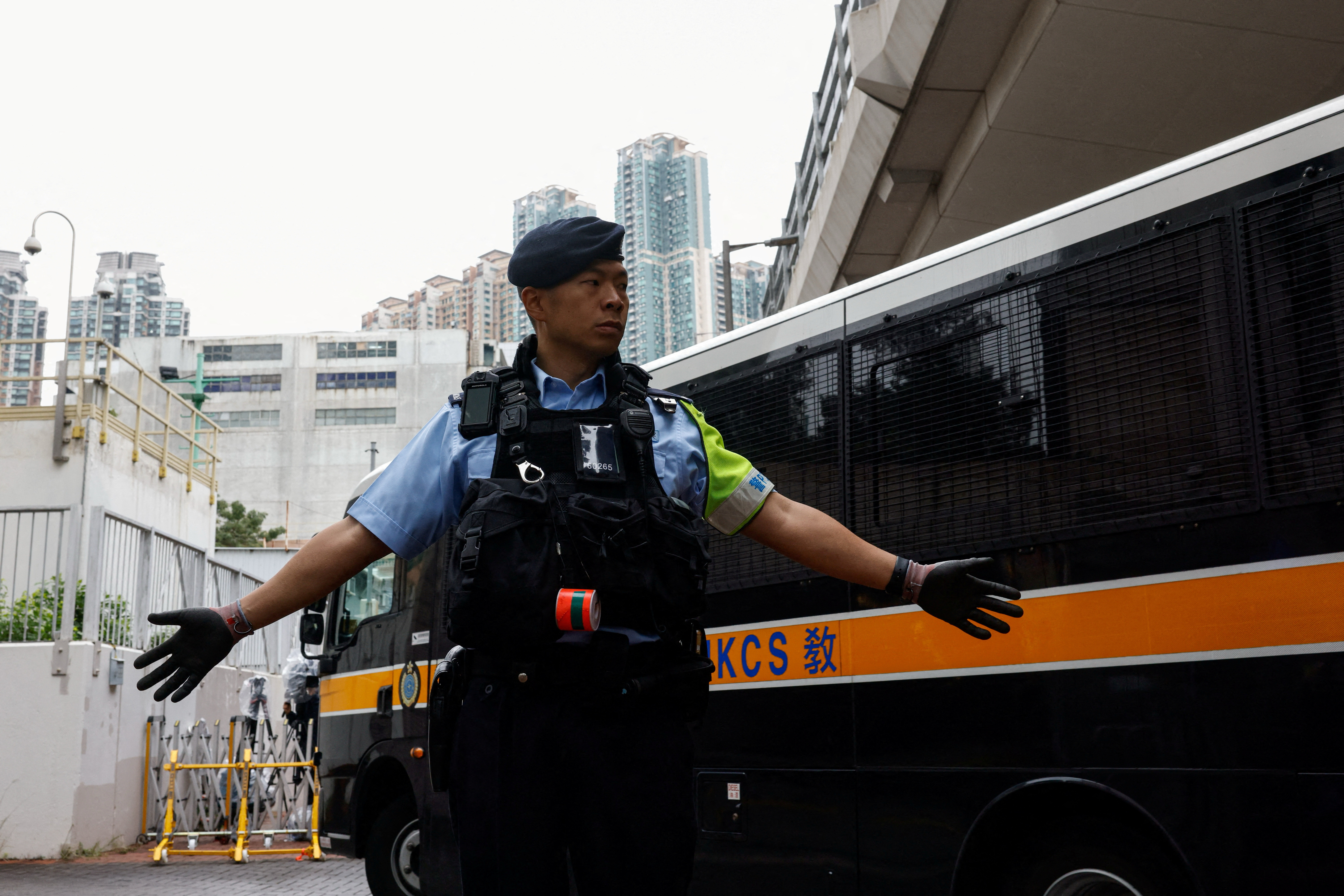 A police officer stands guard as a prison van arrives at the West Kowloon Magistrates' Courts building, ahead of the sentencing of 45 convicted pro-democracy activists charged under the national security law, in Hong Kong