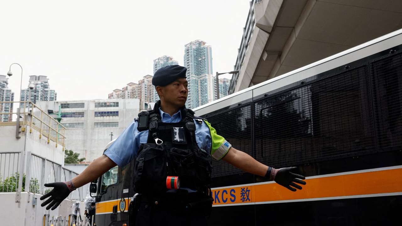 A police officer stands guard as a prison van arrives at the West Kowloon Magistrates' Courts building, ahead of the sentencing of 45 convicted pro-democracy activists charged under the national security law, in Hong Kong