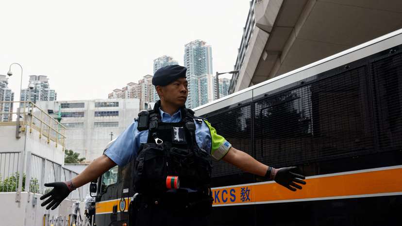 A police officer stands guard as a prison van arrives at the West Kowloon Magistrates' Courts building, ahead of the sentencing of 45 convicted pro-democracy activists charged under the national security law, in Hong Kong