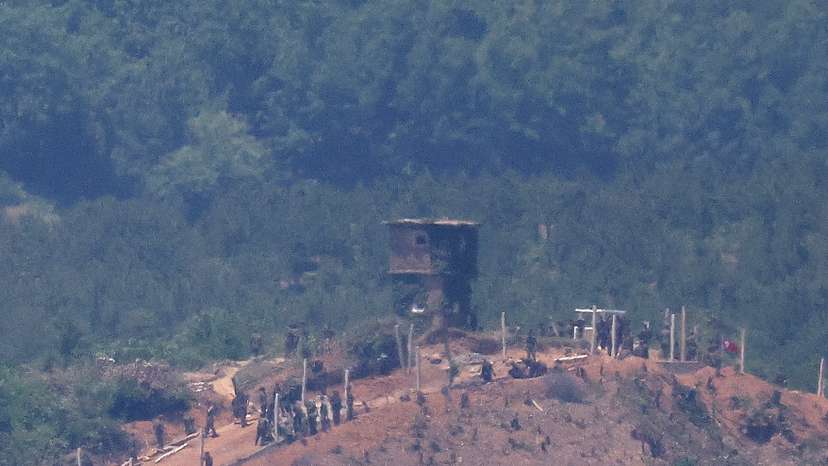 North Korean people work on a military fence near their guard post at the inter-Korean border