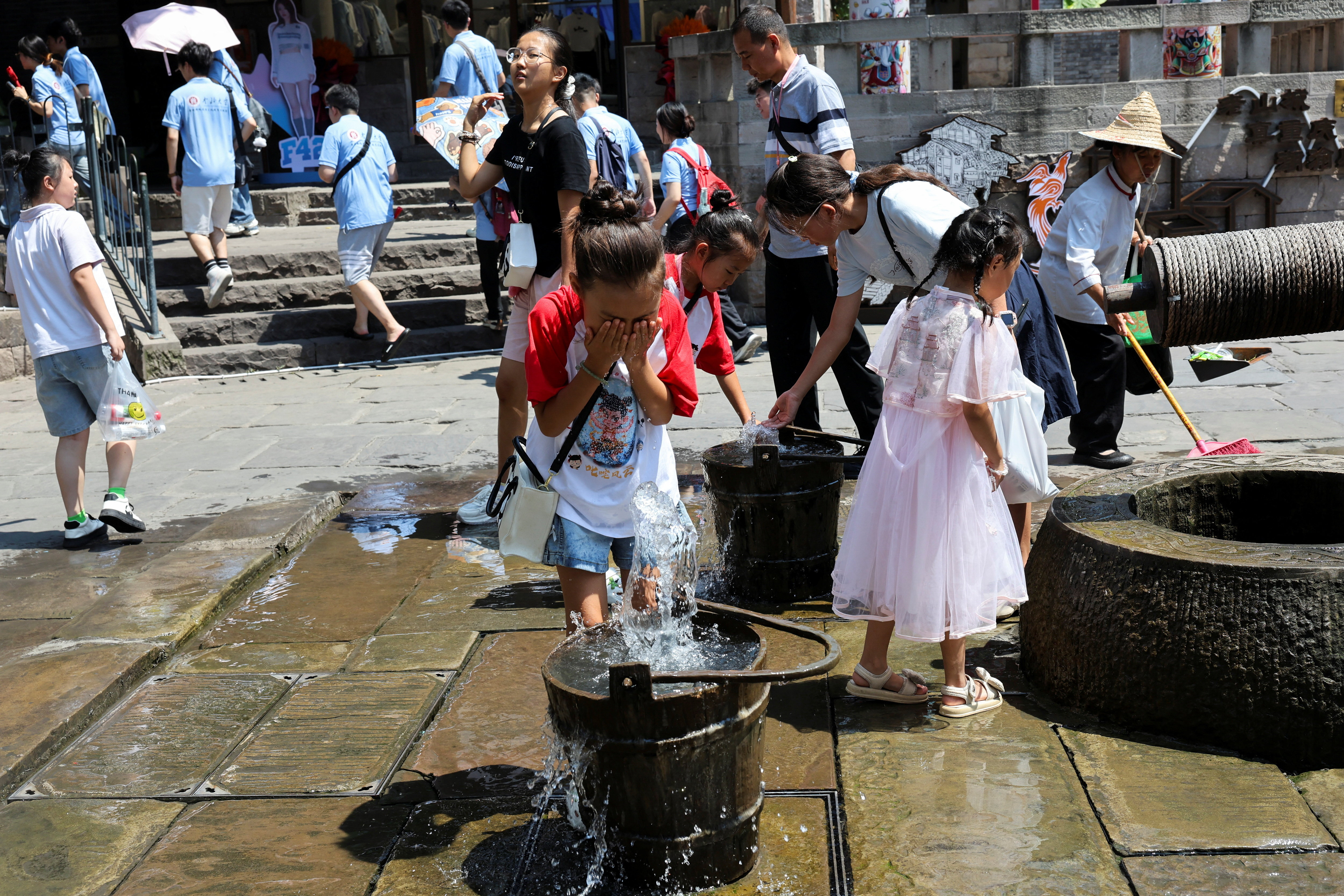 A child rinses her face with water amid a red alert for heat in Chongqing