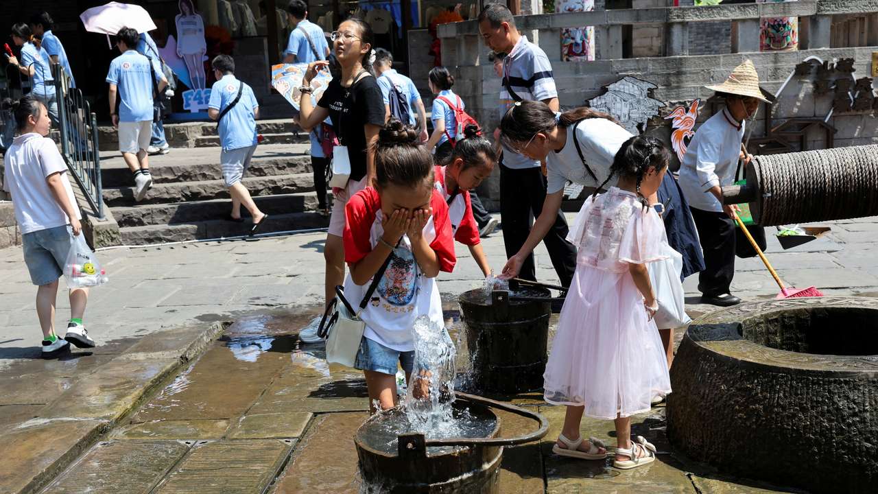 A child rinses her face with water amid a red alert for heat in Chongqing