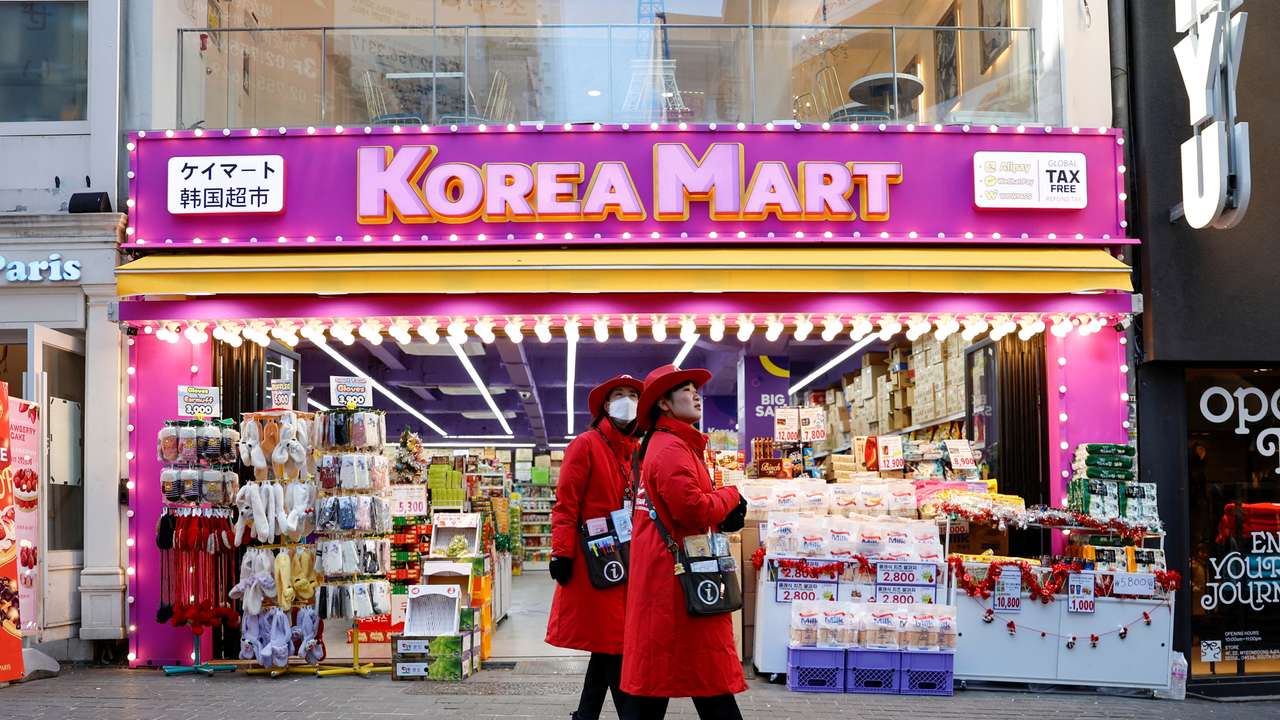 Tourist guides walk next to a Korean Mart at Myeongdong Street in Seoul