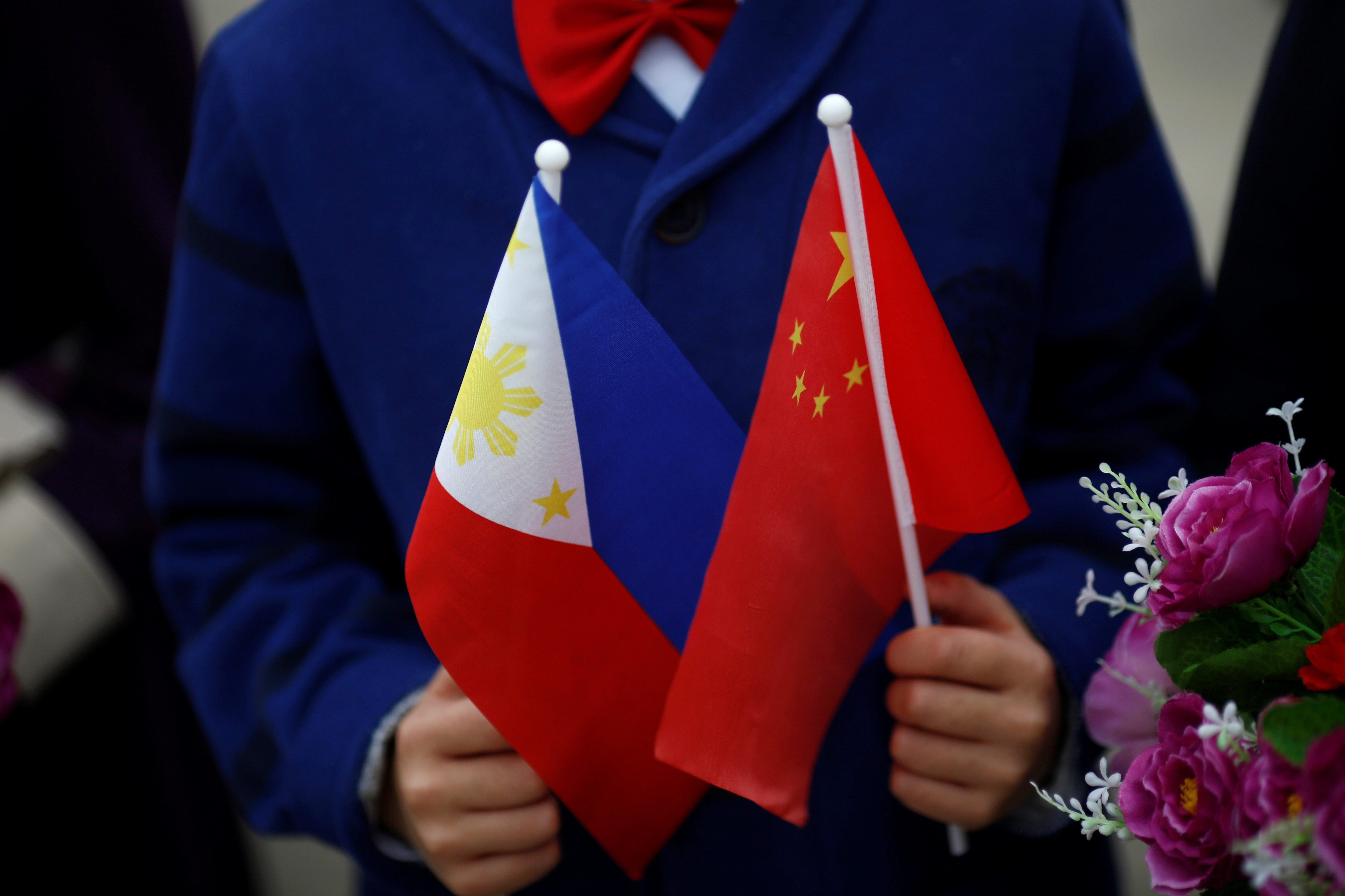 FILE PHOTO: Children hold plastic flowers, national flags of China and the Philippines before President of the Philippines Rodrigo Duterte and China's President Xi Jinping attend a welcoming ceremony at the Great Hall of the People in Beijing