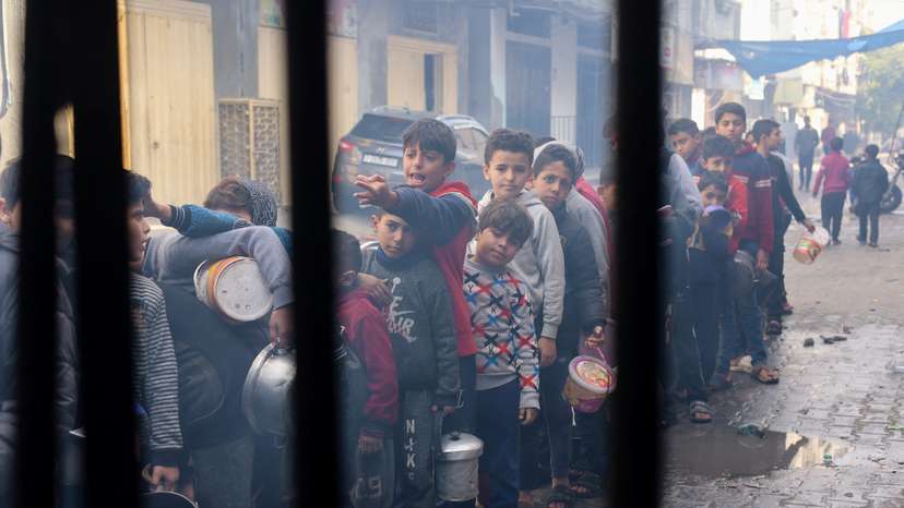 Palestinian children wait to receive food cooked by a charity kitchen, in Rafah