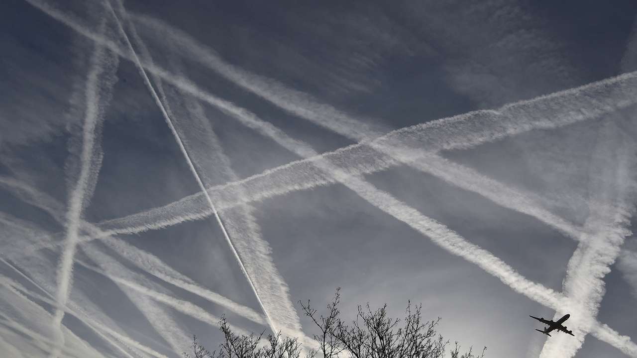 FILE PHOTO: A passenger plane flies through aircraft contrails in the skies near Heathrow Airport in west London