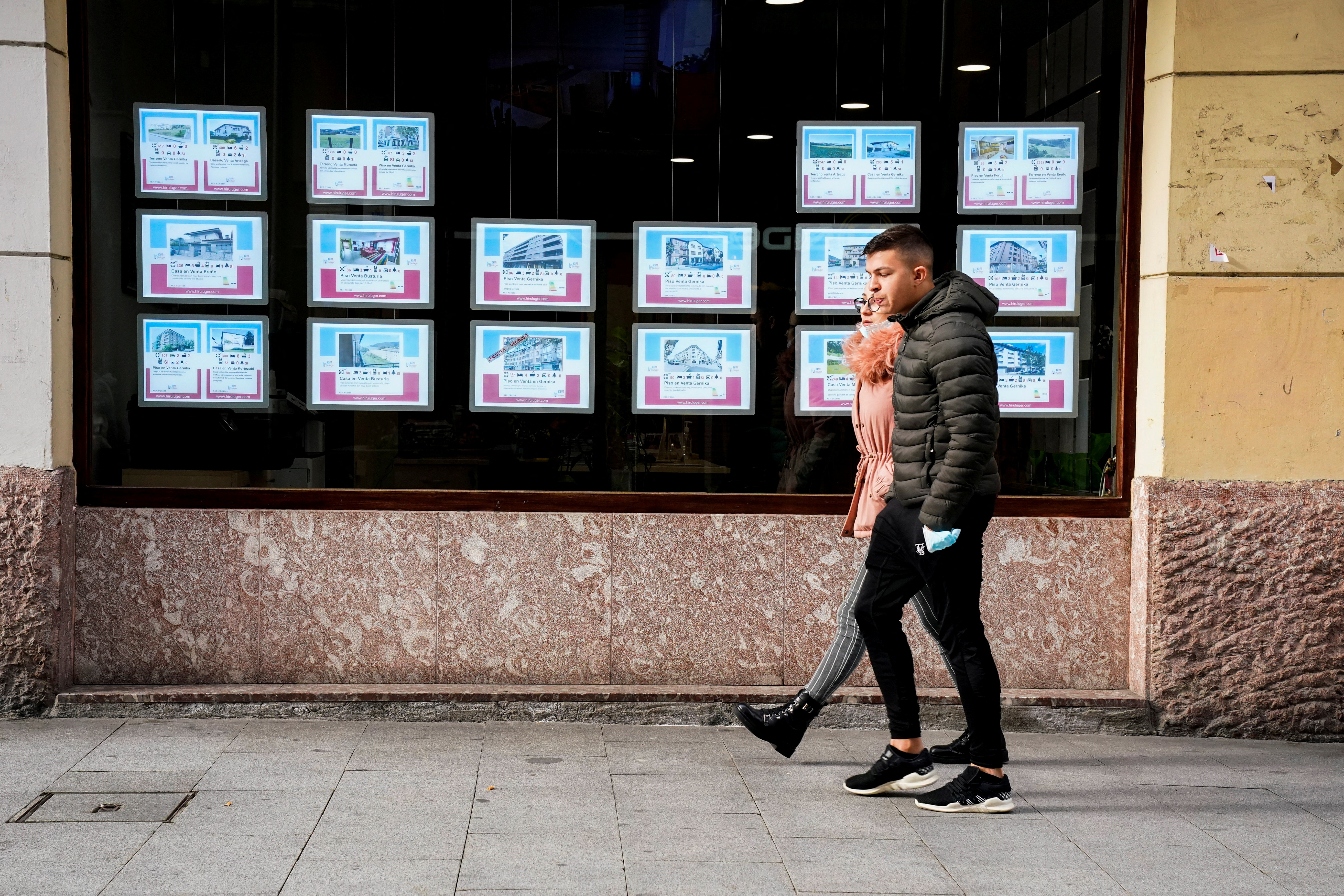 FILE PHOTO: Young people walk past an estate agent in Guernica