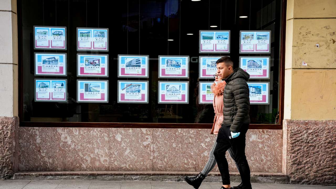 FILE PHOTO: Young people walk past an estate agent in Guernica