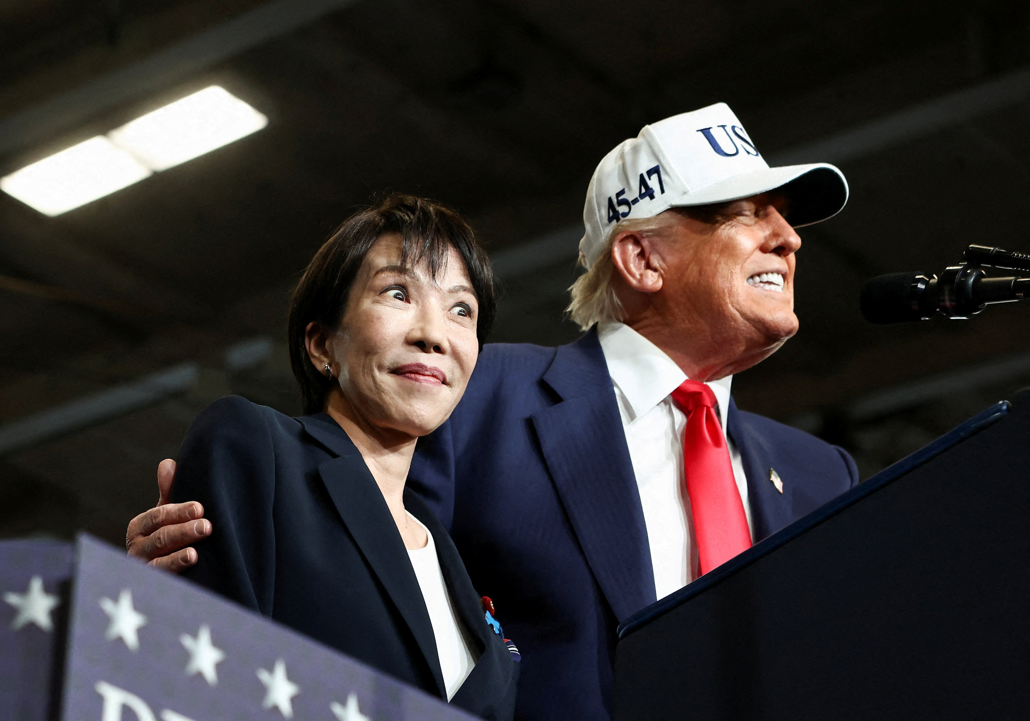 FILE PHOTO: Japanese Prime Minister Sanae Takaichi reacts as U.S. President Donald Trump speaks at U.S. Navy's Yokosuka base in Yokosuka, Japan